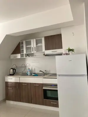 a kitchen with wooden cabinets and a white refrigerator at Апартамент Пирин in Sandanski