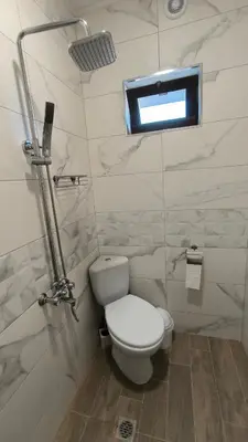 a white bathroom with a toilet and a window at Къща за гости Етерна - Guest house Eterna in Starosel