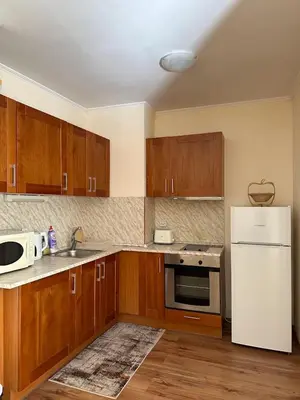 a kitchen with wooden cabinets and a white refrigerator at Cozy Mountain Apartment in Bansko