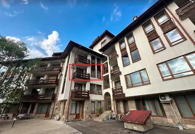 a large apartment building with a red ribbon on it at Cozy Mountain Apartment in Bansko