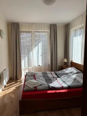 a bedroom with a bed and a large window at Cozy Mountain Apartment in Bansko