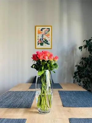 a vase filled with red roses sitting on a table at FREESIA apartment with underground parking in Sofia