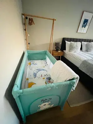 a baby crib in a bedroom with a bed at FREESIA apartment with underground parking in Sofia