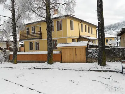 a yellow house with a fence in the snow at Guest House Tsenovi in Koprivshtitsa