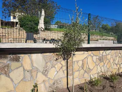 a small tree next to a wall with a fence at Casa Lavandula in Sredno Gradishte