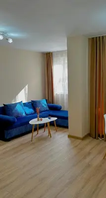 a living room with a blue couch and a table at Bibi Central Apartment Plovdiv in Plovdiv