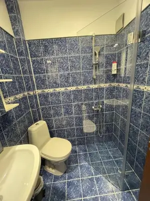 a blue tiled bathroom with a toilet and a shower at Apartment Iztochen blvd, free parking in Plovdiv