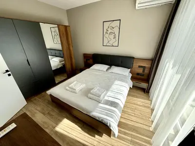 a bedroom with a bed with white sheets and a mirror at AveNew Luxury Apartment 2 in Sofia