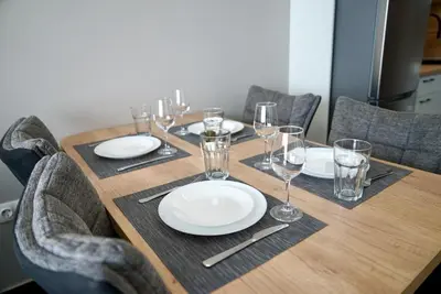 a wooden table with plates and wine glasses on it at AveNew Luxury Apartment 2 in Sofia