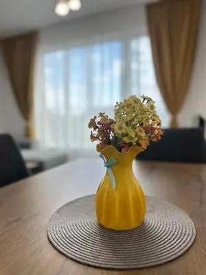 a yellow vase with flowers in it on a table at 1BD Flat near Maritsa river and City Center in Plovdiv