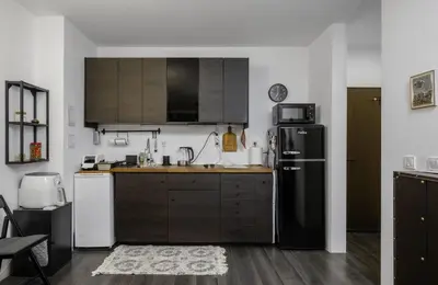 a kitchen with brown cabinets and a black refrigerator at Cozy 1BD Flat Close to the City Center by Flat Mаnager in Sofia