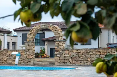 a house with a stone wall and a swimming pool at Къща за гости Casa La Tinozza in Hisarya
