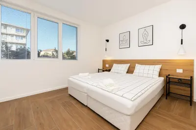 a white bedroom with a large bed and two windows at Cozy and comfortable northern apartment, Kapana district, Plovdiv, Center in Plovdiv