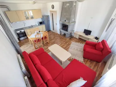a living room with a red couch and a table at Pirin Heights Apartment 200m from SKI ROAD in Bansko