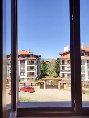 a window view of a parking lot with a red car at Pirin Heights Apartment 200m from SKI ROAD in Bansko