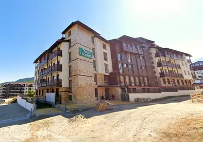 a large brick building with a sign on it at Pirin Heights Apartment 200m from SKI ROAD in Bansko