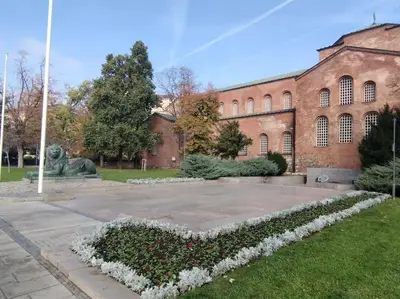 a large brick building with a statue in the yard at The Cathedral in Sofia