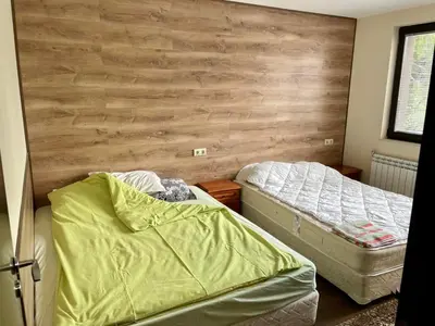 a bedroom with two beds and a wooden wall at St Georgi in Pamporovo