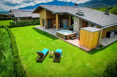 a house with a yard with chairs and a hot tub at Pirin Golf Villa Relax in Razlog