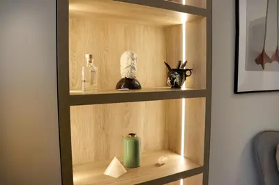 a wooden book shelf with a green candle on it at NEW Glamours Central Suite with Elevator in Sofia