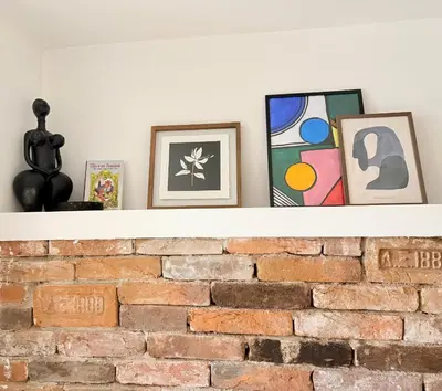 a shelf with pictures on top of a brick fireplace at Central 2 Bedroom Apartments The Quiet Luxury 8 in Plovdiv