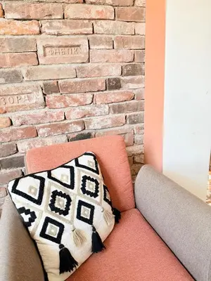 a couch with a pillow on it in front of a brick wall at Central 2 Bedroom Apartments The Quiet Luxury 8 in Plovdiv