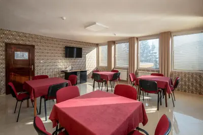 a conference room with red tables and chairs and windows at Balneocomplex Kamena in Velingrad