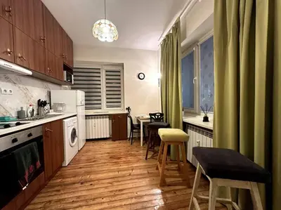 a kitchen with wooden floors and green curtains and a table and chairs at Cultural Retreat in Sofia in Sofia