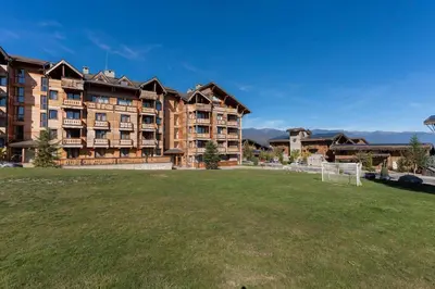 a large apartment building with a soccer field in front of it at Pirin Golf & Country Club Apartment in Bansko