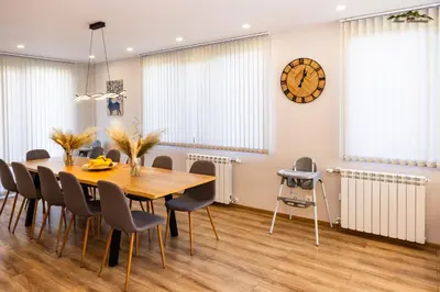 a dining room with a table and chairs and a clock at Villa Malevitsa Вила Малевица in Relyovo