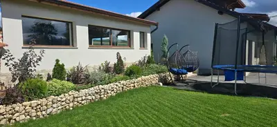 a backyard with a stone wall and a blue table at Villa Malevitsa Вила Малевица in Relyovo