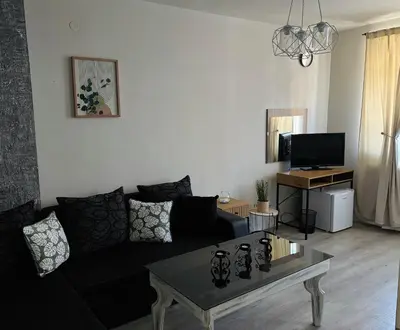 a living room with a black couch and a coffee table at Бутиков Семеен Хотел БРИО in Velingrad