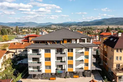 an apartment building in a city with mountains in the background at Комплекс Стадиона in Velingrad