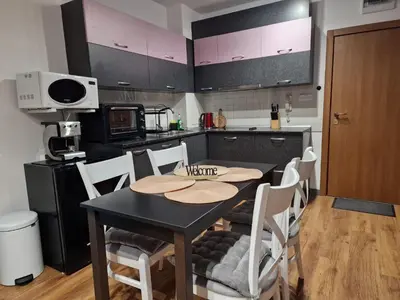 a kitchen with a black table and white chairs at Two-bedroom Apartment Paskalina, near the Ski lift in Bansko