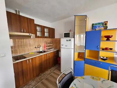 a kitchen with wooden cabinets and a white refrigerator at Apartment Friends in Sandanski