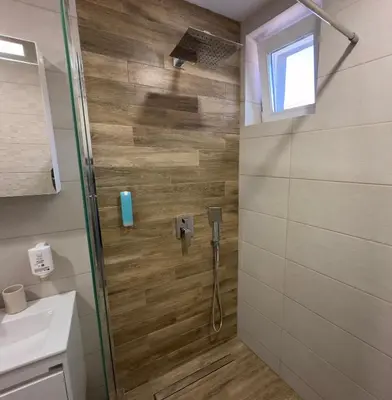 a shower with a glass door in a bathroom at Vimar Apartments in Panagyurishte