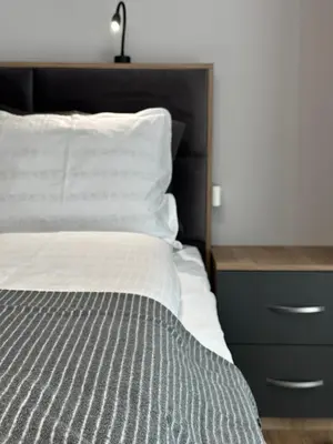 a bed with a black headboard next to a dresser at Vimar Apartments in Panagyurishte