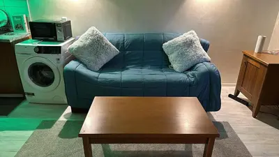 a living room with a blue couch and a washing machine at English Apartments in Bansko