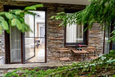 a brick building with a patio with a table and chairs at Large One Bedroom Flat - Mountain Bliss in Borovets