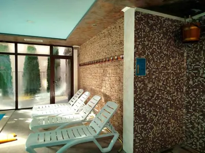 three white chairs sitting in a room with a brick wall at Хотел Релакс in Velingrad