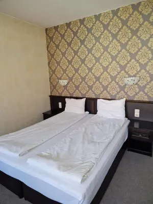 a bedroom with a large bed with white sheets at Хотел Релакс in Velingrad