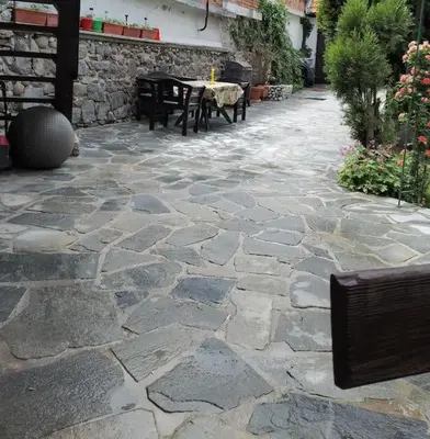 a stone patio with a table and benches on it at Студио в близост до църквата и центъра на града in Bansko