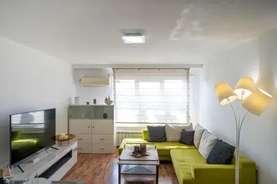 a living room with a green couch and a tv at Bright 1BDR with Balcony in Sofia