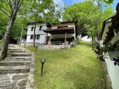 a house with a grass yard next to a building at Forest Hill in Troyan