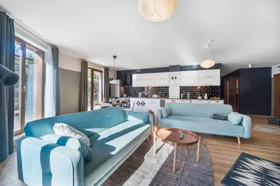 a living room with a blue couch and a kitchen at Host2U New Inn 2 BD, Fireplace, Free parking in Bansko