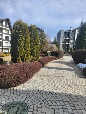 a brick walkway in a park with buildings and trees at Aspen Golf Apartment with Stunning Mountain View in Bansko
