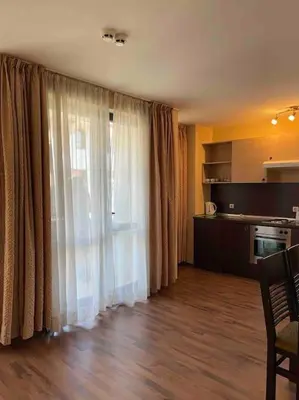 a living room with a large window and a kitchen at Apartment Dream Bansko- 5 min walk to Gondola in Blagoevgrad