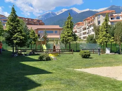 a park with trees and a building and mountains at Apartment Melania in Complex Royal Towers in Bansko