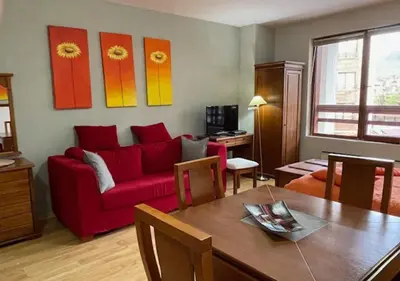 a living room with a red couch and a table at Amber - Mountain Escape with free Bottle of good Wine in Bansko