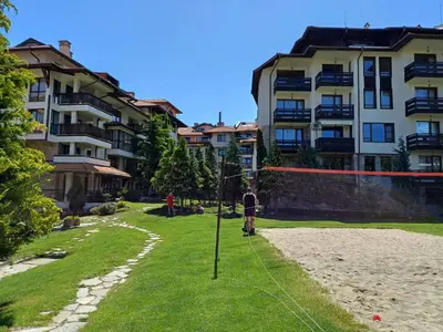 a person is standing in the grass in front of a building at Apartment Melania in Complex Royal Towers in Bansko